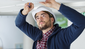 artisan qui visse une ventilation au plafond