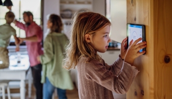 Petite fille qui règle la température du thermostat mural